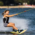 Female wakeboarder wakesurfing. Girl riding waterski cabel. Holding tow rope. Summer activities in the lake.