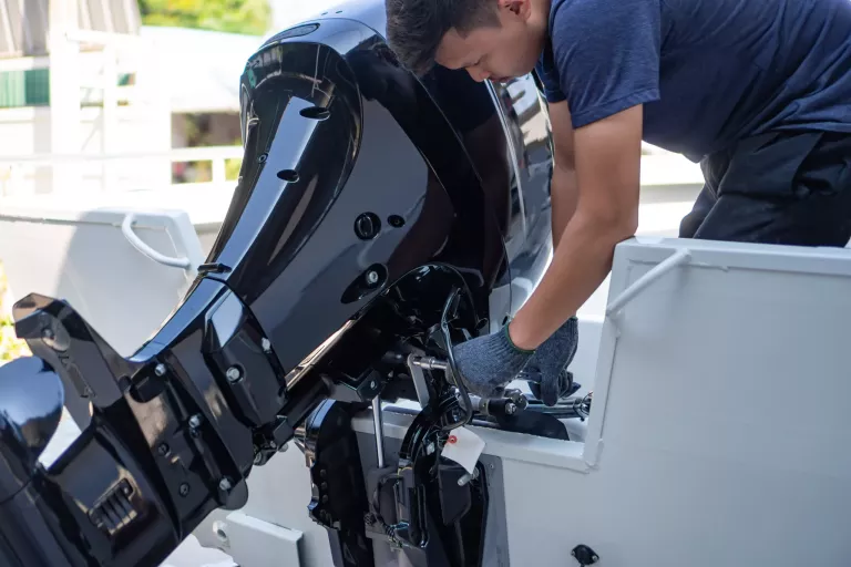 Mechanic is installing speed boat engine , a new engine on an aluminum boat.