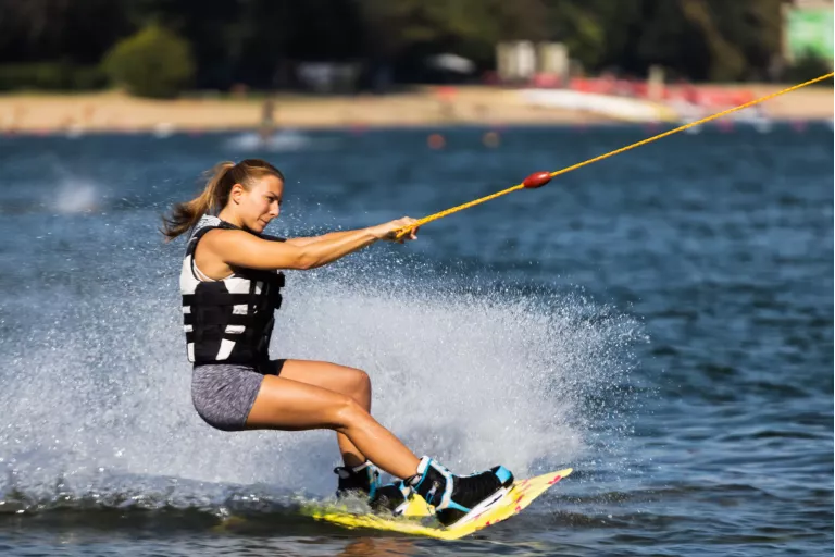 Female wakeboarder wakesurfing. Girl riding waterski cabel. Holding tow rope. Summer activities in the lake.