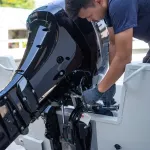 Mechanic is installing speed boat engine , a new engine on an aluminum boat.